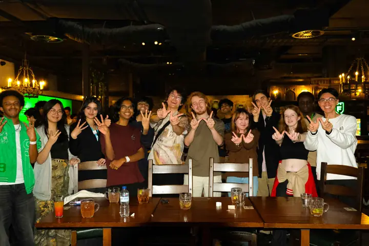 WIRED members making W hand signs at a social event
